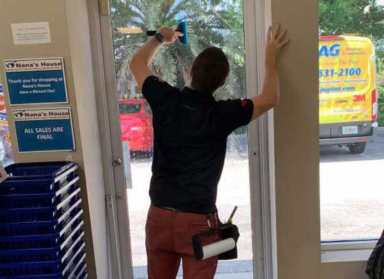 Man installing window tint on the inside of storefront door
