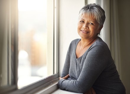 Woman leaning against windowsill enjoying sunshine