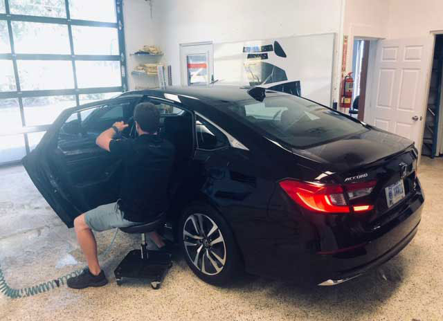 Man installing window tint on a car window