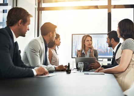 5 people talking in sunny conference room