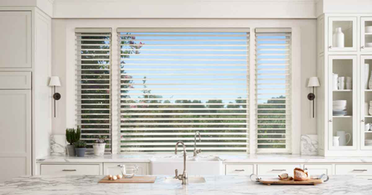 Kitchen window with window coverings and window tint overlooking a green forest in the far background.