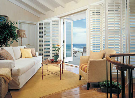 Heritance Hardwood Shutters in a living room with a beach view, like one on Cocoa Beach.
