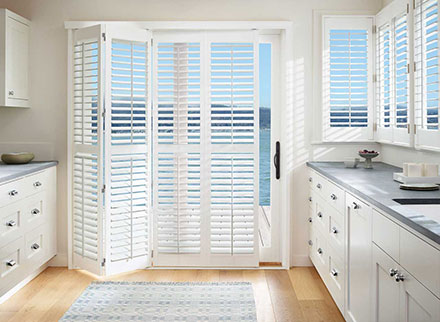 Palm Beach Plantation Shutters compliment a waterfront sliding glass door overlooking the water.