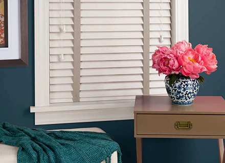 White colored Everwood Hunter Douglas Lake Nona blinds illustrate window coverings inside a dark deal painted room.