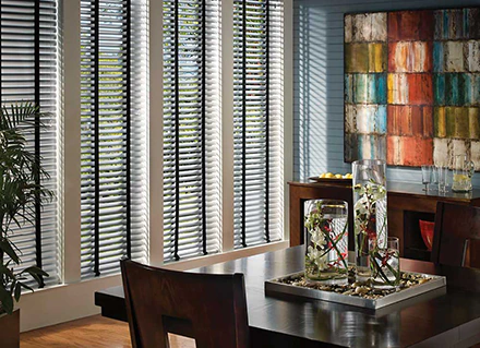 An illustration of Hunter Douglas metal Lake Nona blinds on an office conference room window, along with colorful walls, a painting and table décor.