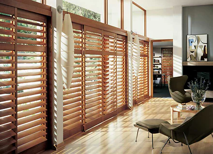 Illustration of how wooden Rockledge plantation shutters can cover a wall of sliding glass doors, provide privacy and filter in the sunlight.