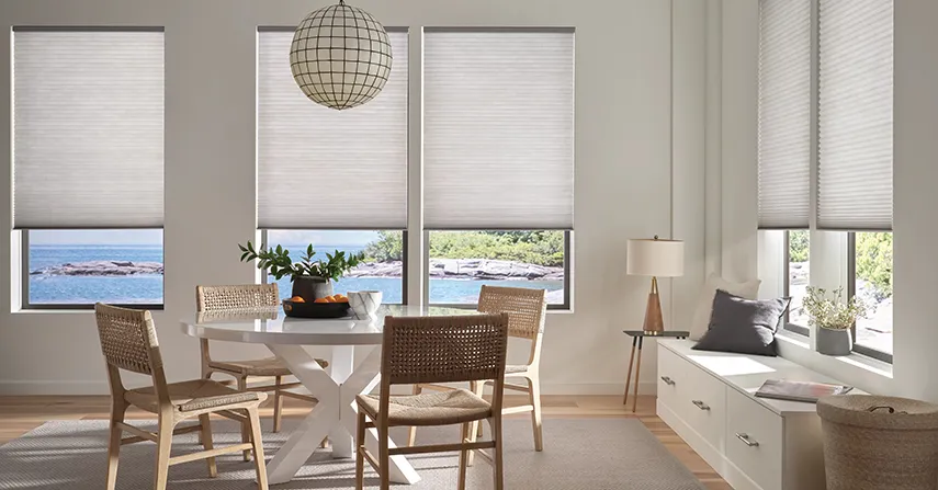 Cellular shades, a window treatment idea, block heat in a dining room with several windows overlooking a waterfront jetty.