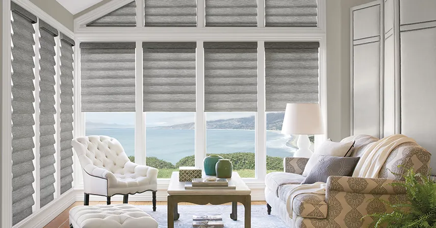 Roman shades, a window treatment idea, cover a living room window overlooking a waterfront bay.