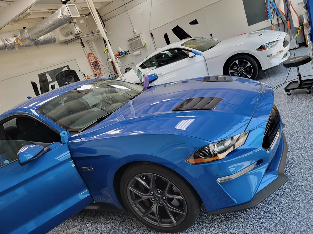 Two cars are inside bays at JAG Window Tinting & Treatments to have auto tint installed.