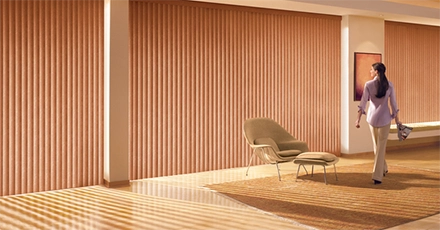 A woman walks down a hallway next to windows covered with Hunter Douglas window treatments.